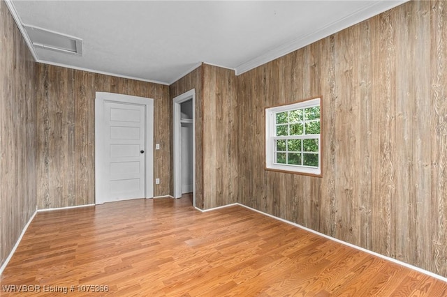 unfurnished room with wood walls, light hardwood / wood-style floors, and crown molding