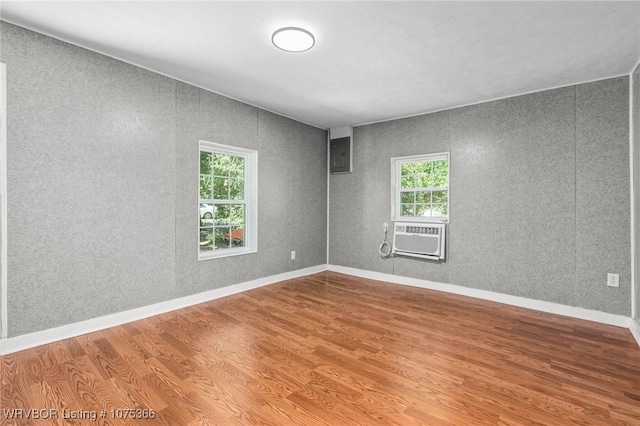 spare room with electric panel, plenty of natural light, cooling unit, and wood-type flooring