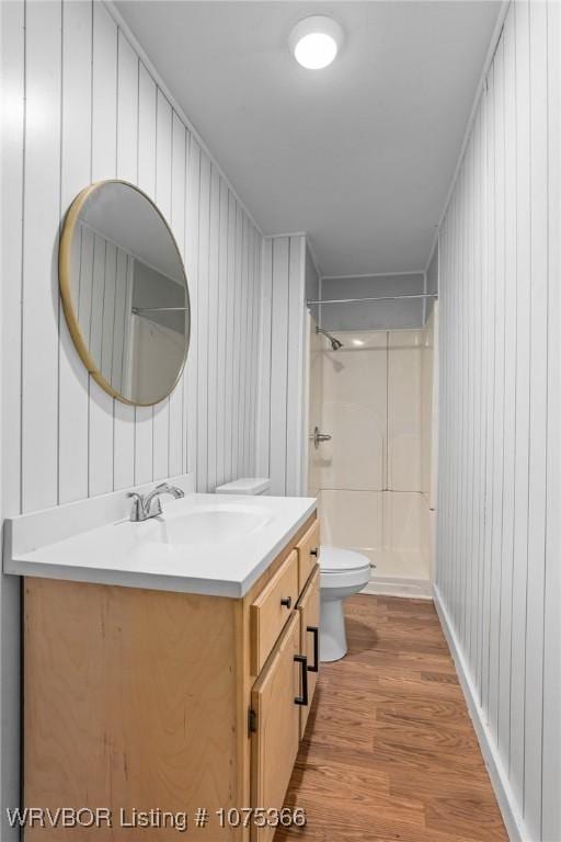 bathroom featuring walk in shower, vanity, wood-type flooring, and toilet