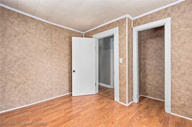 unfurnished bedroom featuring ornamental molding and light hardwood / wood-style flooring