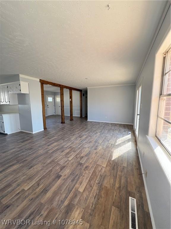19 Lincoln Dr, Charleston, AR 72933 - unfurnished living room with visible vents, crown molding, baseboards, dark wood finished floors, and a textured ceiling