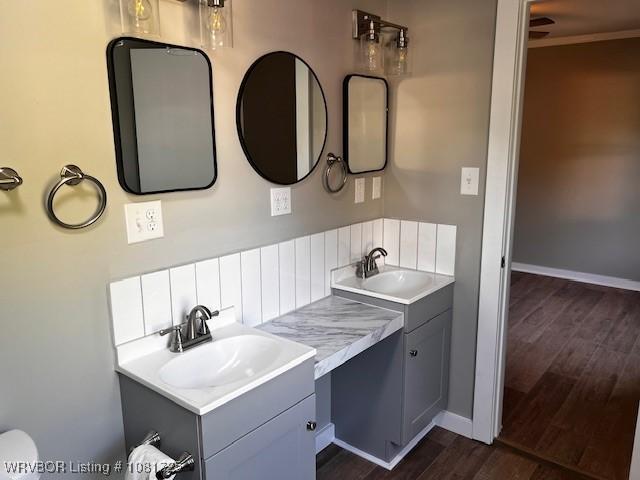 310 Butler St, Lavaca, AR 72941 - bathroom featuring two vanities, wood finished floors, and backsplash