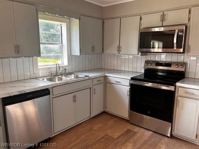 310 Butler St, Lavaca, AR 72941 - kitchen featuring appliances with stainless steel finishes, light wood finished floors, light countertops, ornamental molding, and backsplash