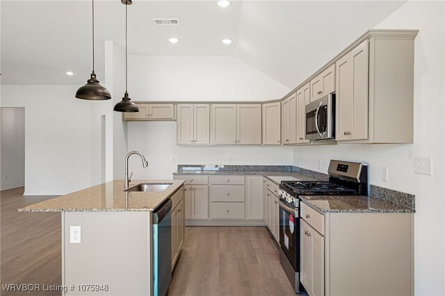 kitchen with dark stone counters, stainless steel appliances, vaulted ceiling, sink, and hanging light fixtures