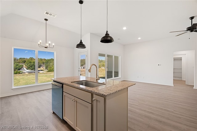 kitchen with light stone counters, a kitchen island with sink, sink, dishwasher, and hanging light fixtures