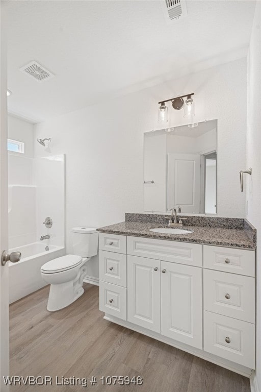 full bathroom with washtub / shower combination, hardwood / wood-style floors, vanity, and toilet