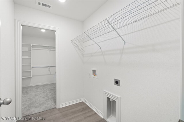 clothes washing area with hookup for an electric dryer, hookup for a washing machine, and hardwood / wood-style flooring