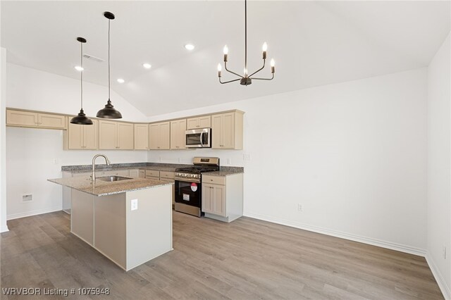 kitchen with pendant lighting, stainless steel appliances, light stone counters, and sink