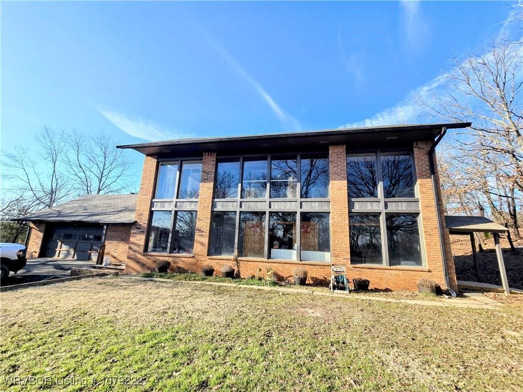 exterior space featuring a garage, brick siding, and a lawn