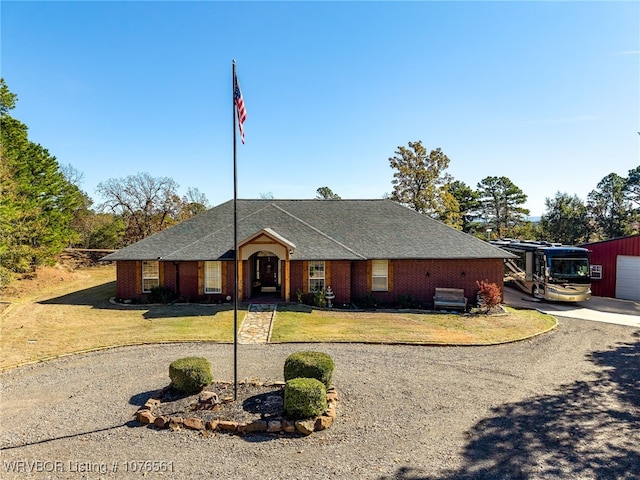 single story home featuring a garage, an outdoor structure, and a front yard