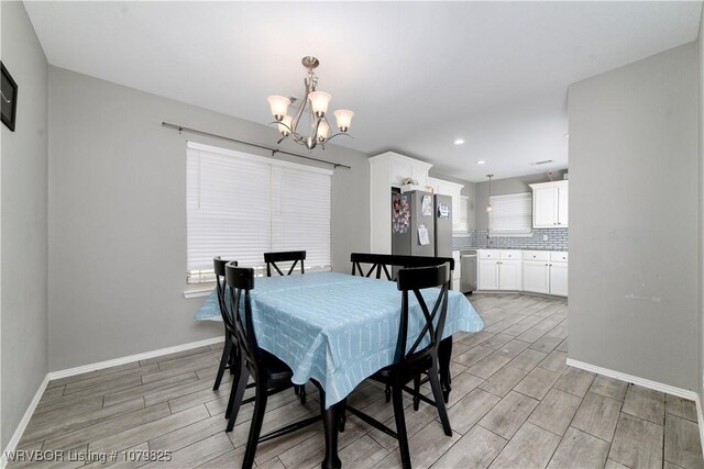 138 Stone Dr, Roland, OK 74954 - dining area featuring wood finish floors, a notable chandelier, baseboards, and a healthy amount of sunlight