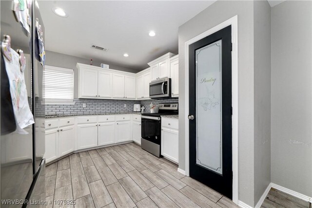 138 Stone Dr, Roland, OK 74954 - kitchen with decorative backsplash, visible vents, stainless steel appliances, white cabinetry, and wood tiled floor