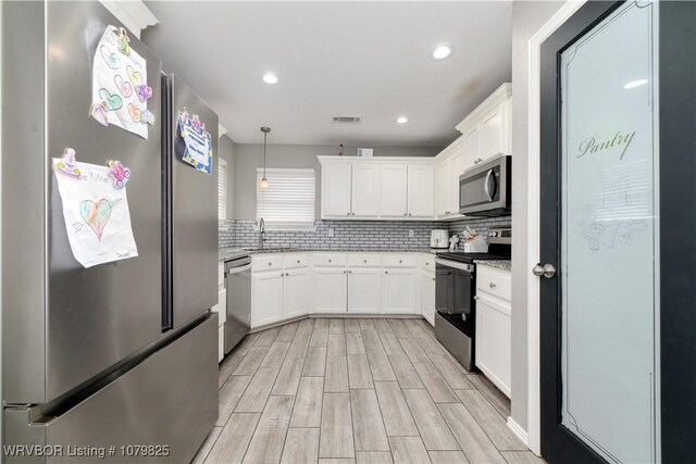 138 Stone Dr, Roland, OK 74954 - kitchen with stainless steel appliances, white cabinetry, wood tiled floor, a sink, and backsplash