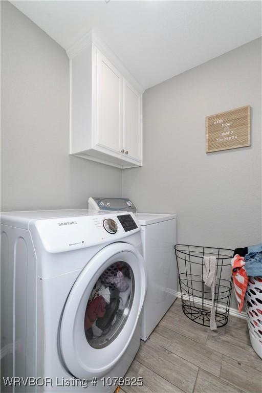 138 Stone Dr, Roland, OK 74954 - clothes washing area with baseboards, cabinet space, light wood-style flooring, and washer and clothes dryer