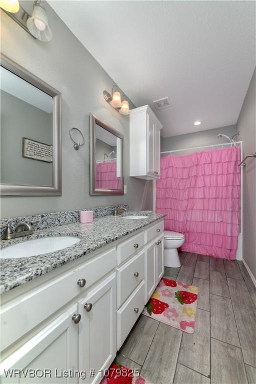 138 Stone Dr, Roland, OK 74954 - full bathroom featuring toilet, a sink, double vanity, and wood tiled floor