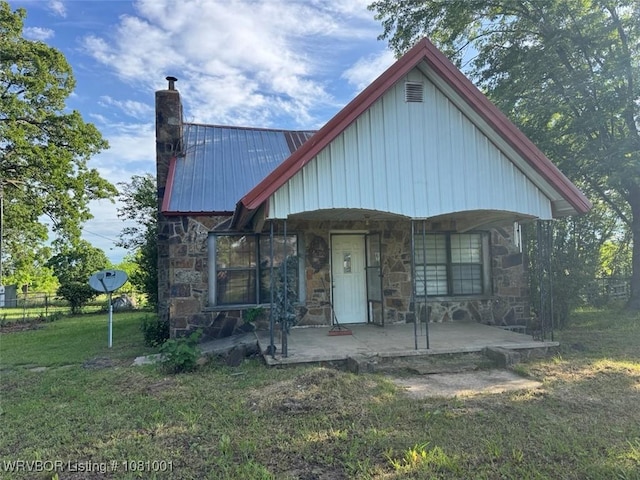 464085 E 1020th Rd, Sallisaw, OK 74955 - view of front of home featuring stone siding, a chimney, a front lawn, covered porch, and metal roof