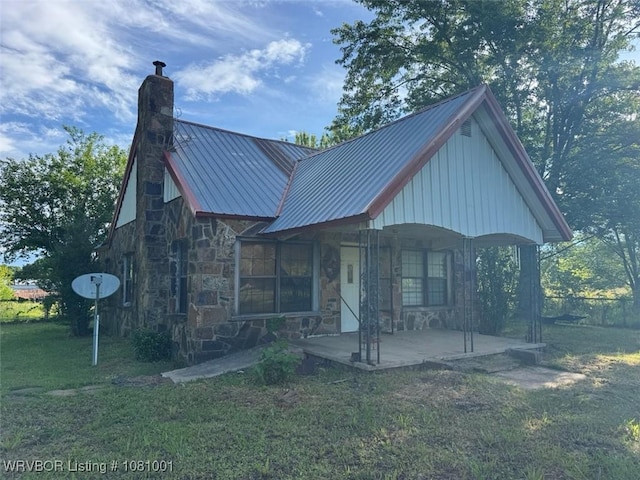 464085 E 1020th Rd, Sallisaw, OK 74955 - view of front facade with a chimney, stone siding, a porch, a front yard, and metal roof