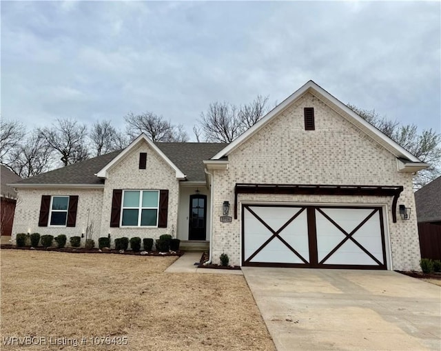 view of front of property featuring brick siding, a front yard, roof with shingles, a garage, and driveway