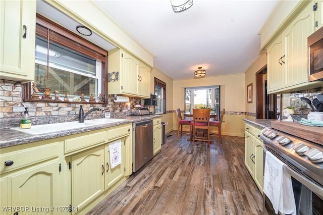 kitchen featuring stainless steel appliances, tasteful backsplash, dark wood-type flooring, and sink