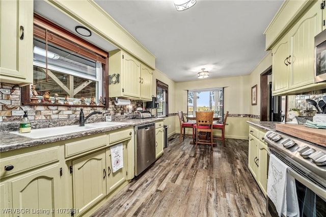 kitchen with appliances with stainless steel finishes, backsplash, hardwood / wood-style flooring, and sink