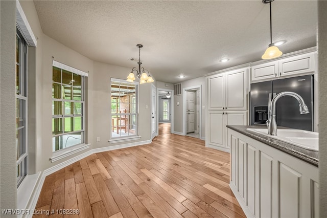 6721 Dean Rd, Alma, AR 72921 - kitchen with fridge with ice dispenser, white cabinetry, a chandelier, light wood-style floors, and a textured ceiling