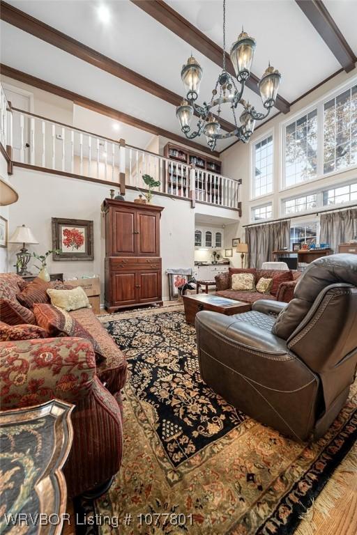 living area with beam ceiling, an inviting chandelier, and a high ceiling