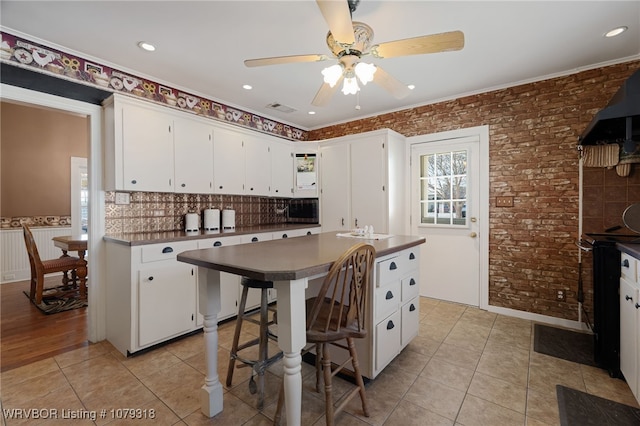 kitchen featuring brick wall, light tile patterned flooring, dark countertops, and visible vents