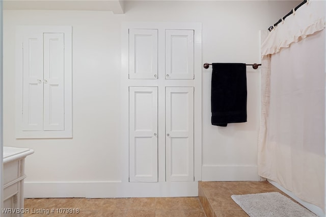 bathroom featuring a shower with shower curtain, tile patterned floors, and baseboards
