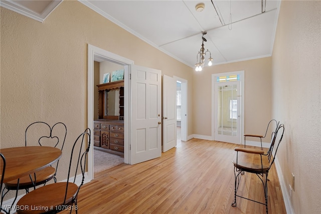 foyer entrance with a textured wall, crown molding, and light wood finished floors