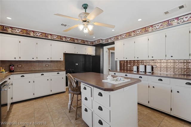 kitchen featuring dark countertops, light tile patterned floors, visible vents, and white cabinets