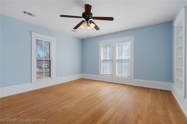 spare room featuring light wood-style floors, visible vents, baseboards, and a ceiling fan