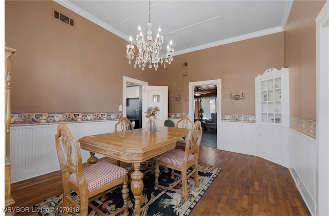dining space featuring a wainscoted wall, wood finished floors, visible vents, and crown molding