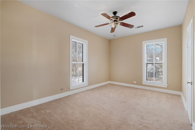 carpeted spare room with visible vents, ceiling fan, and baseboards