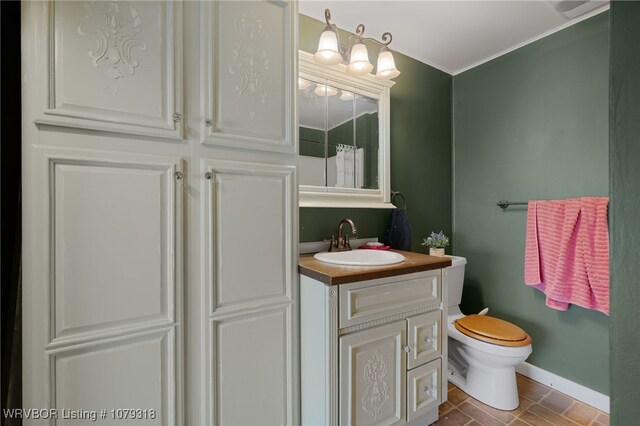 bathroom featuring toilet, baseboards, and vanity