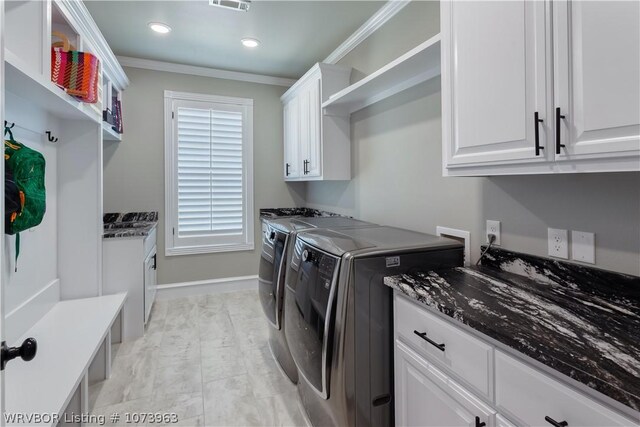 clothes washing area with separate washer and dryer, cabinets, and ornamental molding