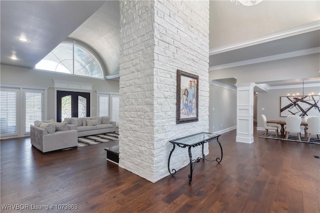 interior space with decorative columns, dark wood-type flooring, a towering ceiling, and a chandelier