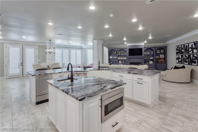 kitchen with dark stone counters, a spacious island, sink, appliances with stainless steel finishes, and kitchen peninsula