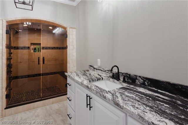 bathroom featuring vanity, a shower with door, and ornamental molding