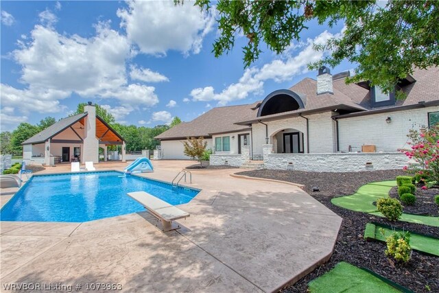 view of swimming pool with a diving board, a patio area, and a water slide