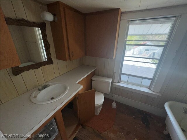 1221 S 3rd St, Stilwell, OK 74960 - bathroom featuring wood-type flooring, toilet, wood walls, a freestanding tub, and vanity