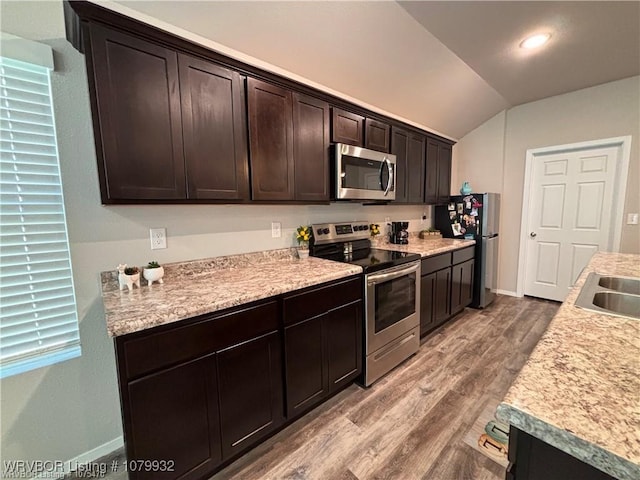 kitchen with light countertops, lofted ceiling, dark brown cabinets, appliances with stainless steel finishes, and wood finished floors
