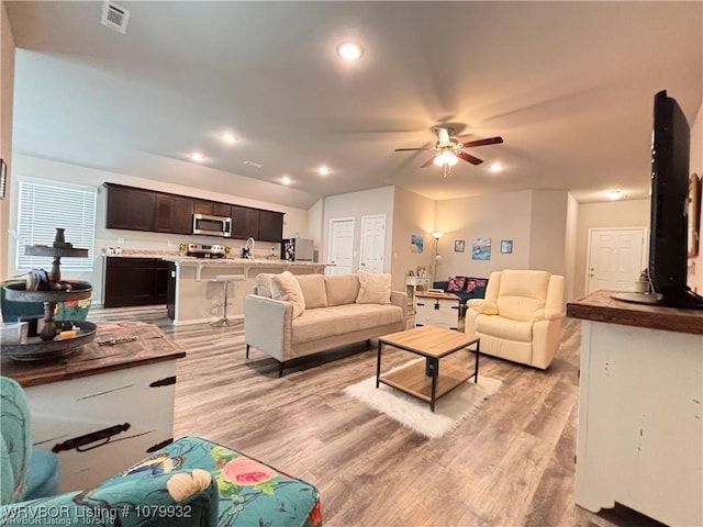 living area featuring lofted ceiling, light wood-type flooring, recessed lighting, ceiling fan, and visible vents