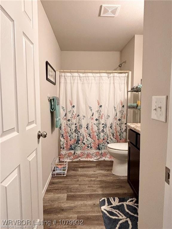 full bathroom featuring visible vents, toilet, wood finished floors, vanity, and curtained shower