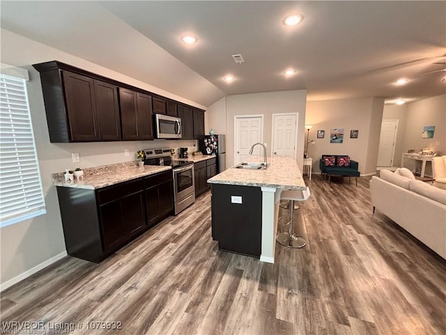 kitchen with open floor plan, a kitchen breakfast bar, a sink, visible vents, and appliances with stainless steel finishes