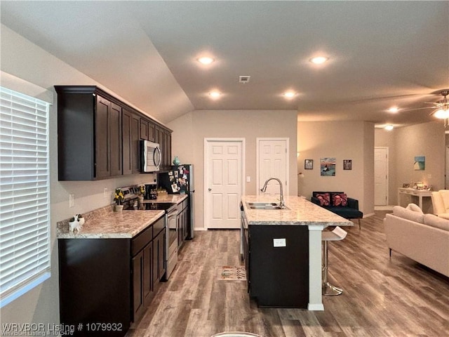 kitchen featuring open floor plan, a sink, appliances with stainless steel finishes, and wood finished floors