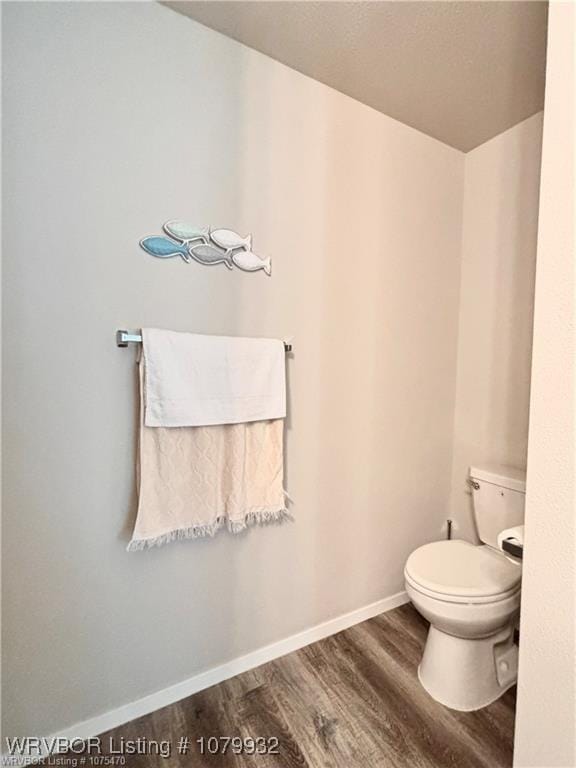 bathroom with baseboards, wood finished floors, and toilet