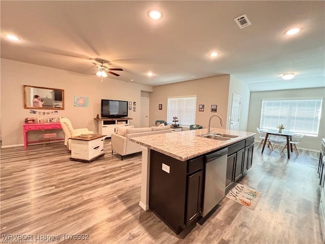 kitchen with light wood-style flooring, visible vents, a center island with sink, a sink, and stainless steel dishwasher