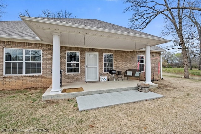 1111 Ridge Dr, Stilwell, OK 74960 - doorway to property featuring roof with shingles, a patio area, and brick siding