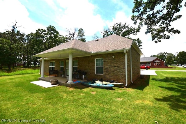 1111 Ridge Dr, Stilwell, OK 74960 - back of property featuring a yard, brick siding, a patio area, and a shingled roof