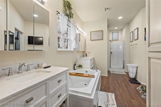 1111 Ridge Dr, Stilwell, OK 74960 - full bathroom featuring wood finished floors, two vanities, a bath, a shower stall, and baseboards